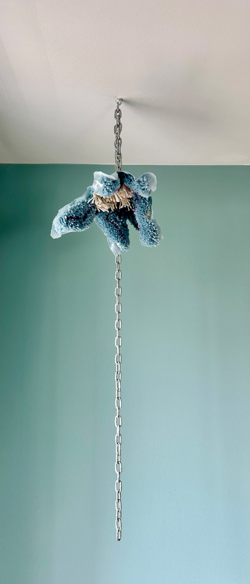 Hang Flower — a suspended tufted flower in dusty blue and cream tones hanging from a silver chain