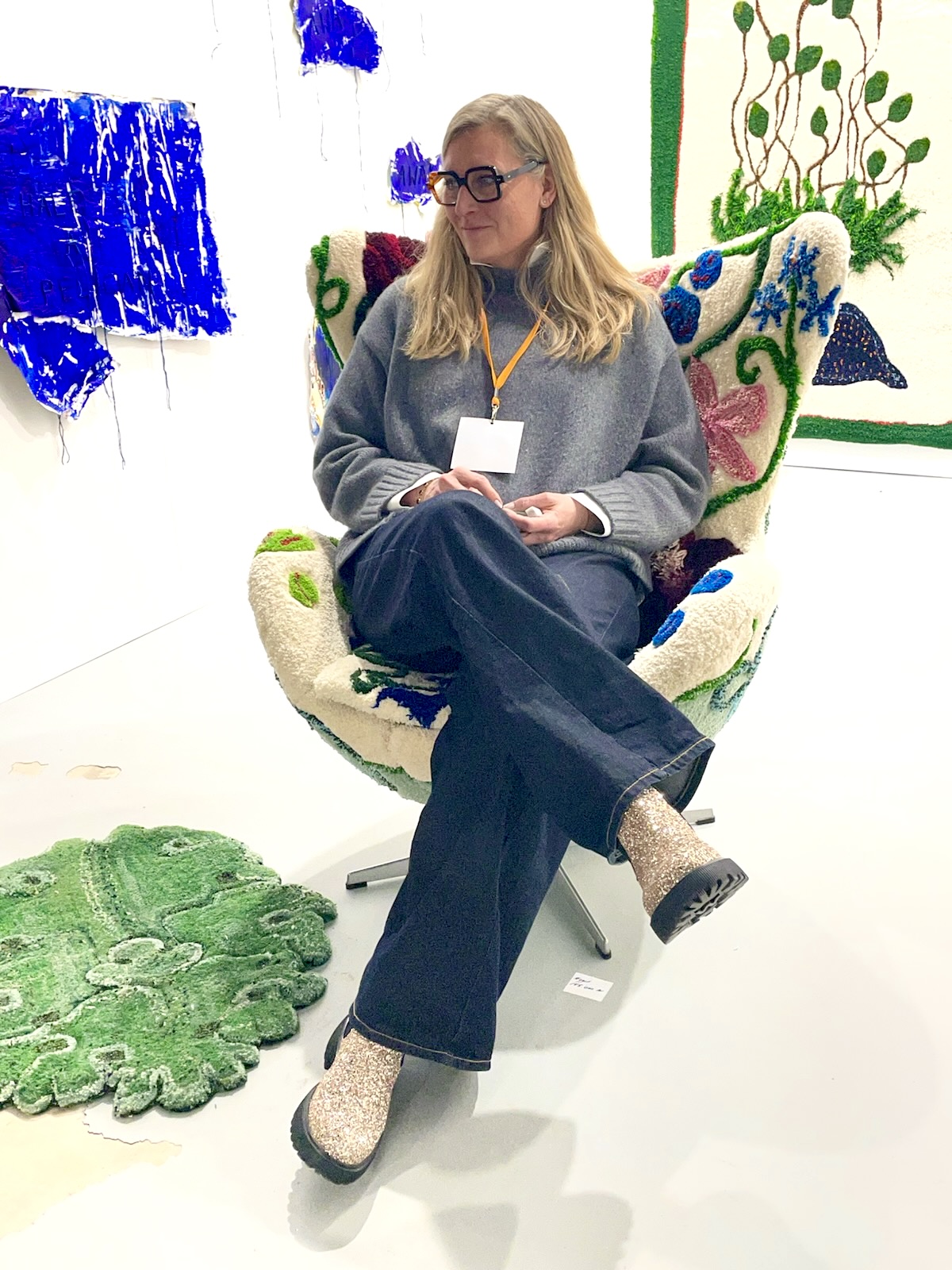 Pernille Agerskov seated in a hand-tufted wool armchair surrounded by her works